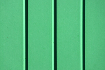 Fototapeta premium Green corrugated metal texture background surface with vertical ridges and shadows
