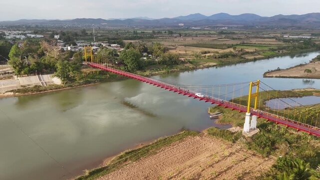 Aerial view of the iconic red Kon Klor suspension bridge over a river in Kon Tum, Vietnam