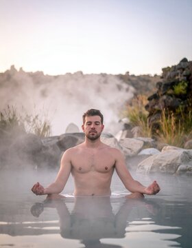 Man Meditating in Natural Hot Springs with Steam.