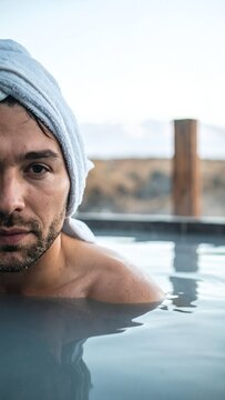 Man with towel on head relaxing in a hot spring pool.
