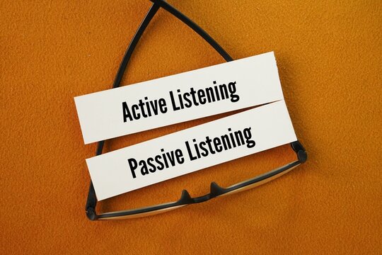 Glasses and paper with the words active listening and passive listening. A key difference between active and passive listening is the response of the listener