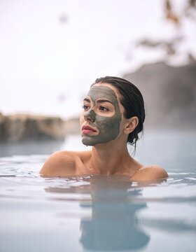 Woman with mud mask relaxing in geothermal spa.