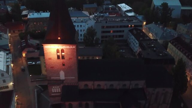 Cinematic night aerial view of St. Johns Church (Jaani kirik) and the historic Tartu Old Town.