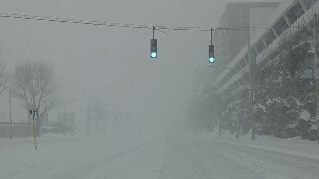 Two stop lights swaying during a snow blizzard on a local snow covered empty road