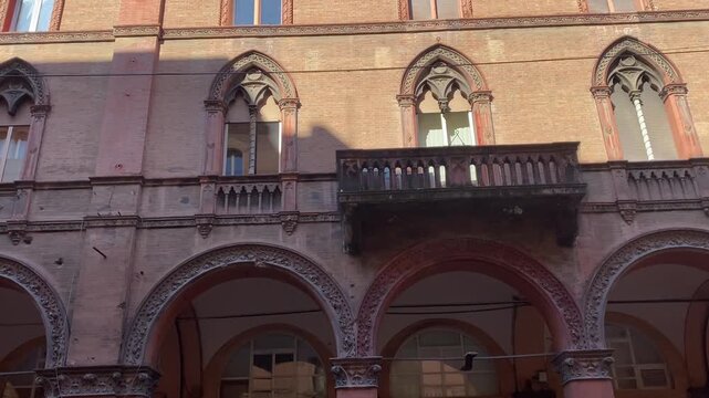 Historic building facade with porticos and gothic windows in Via Indipendenza, Bologna, Italy.