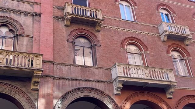 Historic palace facade with ornate balconies and porticos in Bologna, Italy.