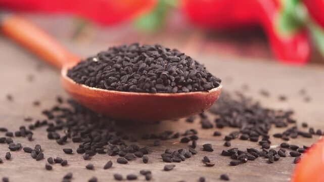 Black cumin seeds on wooden spoon in kitchen setting
