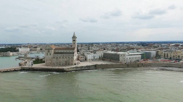 Aerial view of the Trani Cathedral in Puglia in Italy, at the waterfront, drone circling, slow reveal of the city