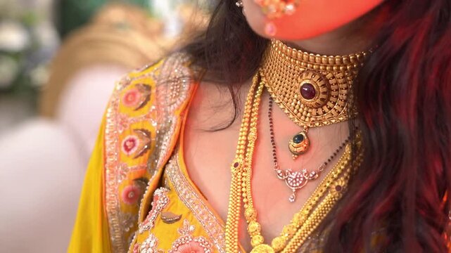 Regal Indian bridal look: A young woman showcasing intricate gold ornaments and ethnic wedding fashion in a studio setting.