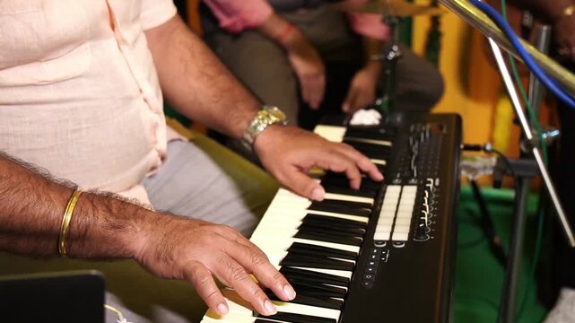 A man playing synthesiser piano in a band in India