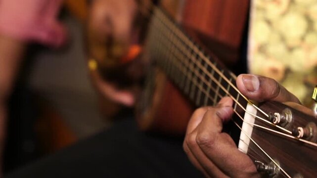 Close-up shot of a man playing an acoustic guitar in India