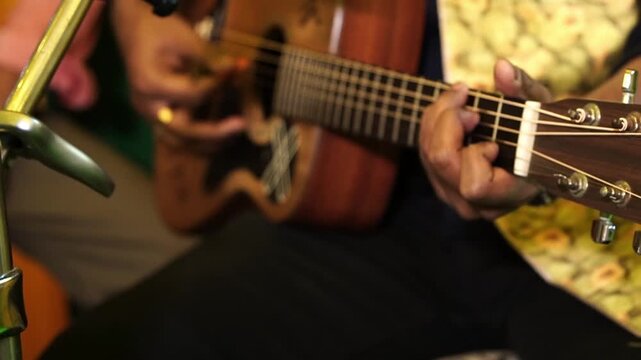 An Indian guitarist playing a wooden acoustic guitar, showcasing musical talent and modern youth culture in South Asia