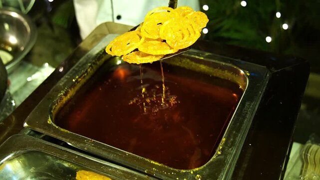 Close-up of traditional Indian sweet Jalebi being deep-fried to golden perfection in a bubbling vat of oil.