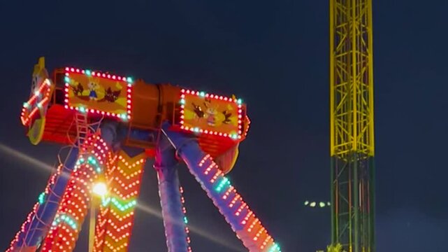 Illuminated Carnival Pendulum Ride Swings Against the Night Sky with Bright Lights