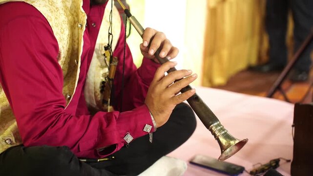 Skilled artist playing the shehnai, a ceremonial Indian oboe, at a festive marriage celebration in India.