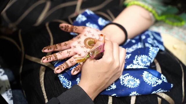 Close-up of a henna artist applying intricate Mehendi designs on an Indian girl's hand during a traditional celebration