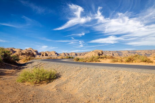 Winding asphalt road through arid desert landscape with rock formations under blue sky. road trip concept