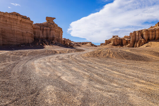 Sandy road winding through rugged canyon rock formations in Xinjiang, China