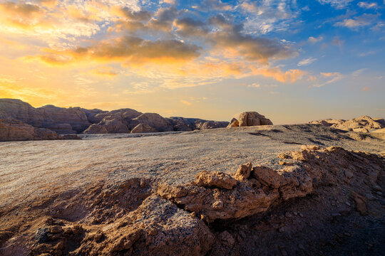 Rocky desert valley under a dramatic sunset sky at golden hour. Scenic canyon landscape in Xinjiang, China.
