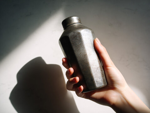 Hand Holding Metal Thermos Shaker Bottle Close-Up, Fitness Hydration and Beverage Concept