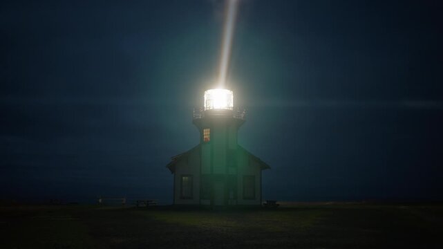 Night view of Point Cabrillo Lighthouse glowing through light coastal fog, powerful rotating beacon cutting the dark sky above Mendocino, California, USA creating dramatic maritime atmosphere