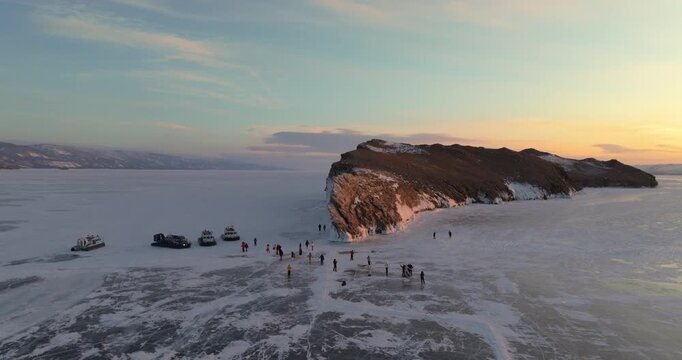 Ogoy island in winter Baikal lake, Siberia, Russia. Aerial view. Tourists walking around the island. Cars and hovercrafts ride on the ice. Winter landscape