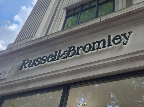 London UK 03.07.2025 Russell & Bromley luxury footwear store sign on elegant stone facade with modern lighting and reflections on glass windows in upscale shopping district