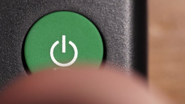 Macro view of green power button with white icon on black control panel