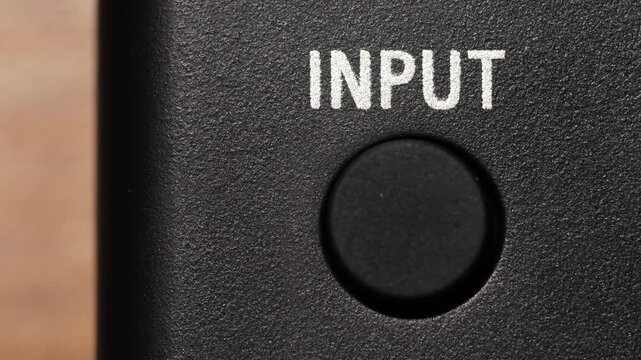 Macro view of finger pressing black input button below white text on black panel