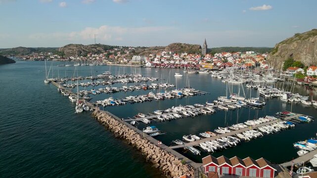 Drone flight over scenic marina and traditional red boathouses in Fiskeb&auml;ckskil village on Skaft&ouml; island during sunny summer day in Bohusl&auml;n Sweden