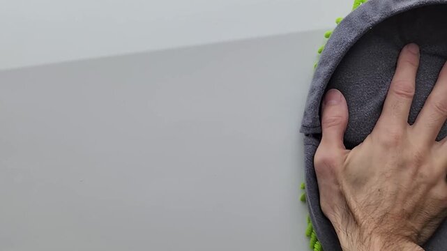 Extreme close-up of a hand using a microfiber wash mitt to polish a clean white car surface. Smooth motion highlights detailing, cleaning, and car care concept.