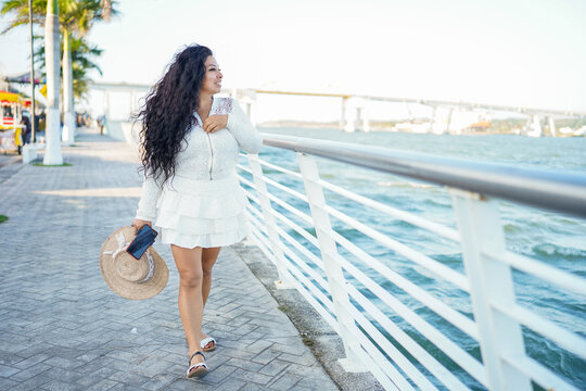 Latina woman enjoying summer travel on waterfront promenade