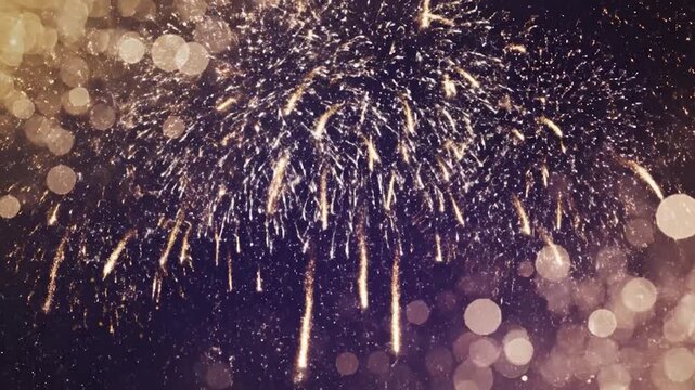 A vibrant display of golden fireworks exploding against a dark background with soft bokeh light effects