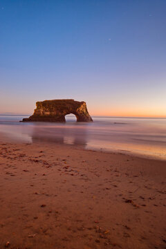 Natural Rock Arch at Santa Cruz Seaside with Motion Blur Waves and Clear Blue Sky