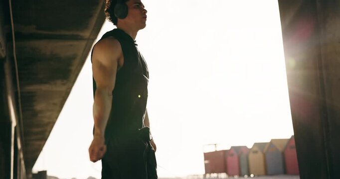 Exercise, headphones and man with jump rope at beach, bodybuilder and training for cardio or fitness. Athlete, skipping and person with equipment for workout routine, streaming and music in nature