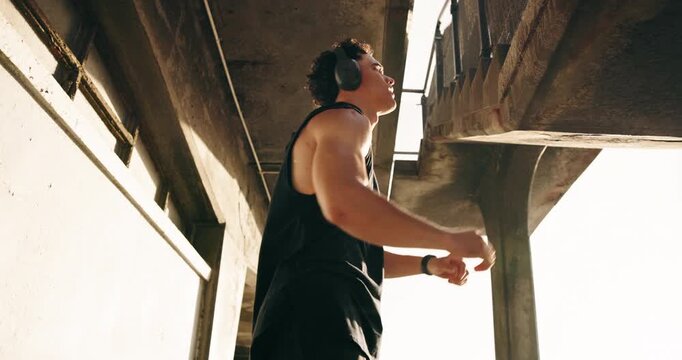 Stretching, runner and headphones with man at beach for workout start, health radio and streaming. Warm up, training podcast and low angle with person outdoor for fitness, wellness and challenge