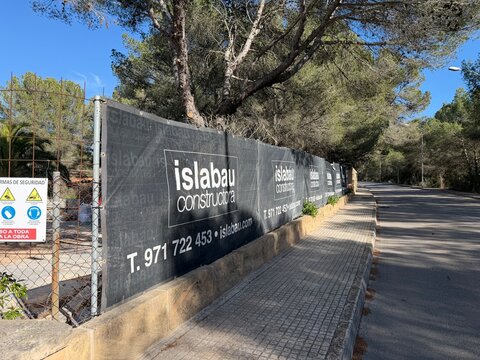 Santa ponsa, spain, march 30, 2026 construction site boundary with islabau constructora banners and safety signs along a sunny urban road