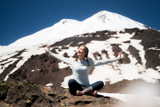 A young woman is enjoying mountain acclimatization in the summer sun, with open arms and enjoying the freedom of being outdoors. Active and healthy lifestyle.