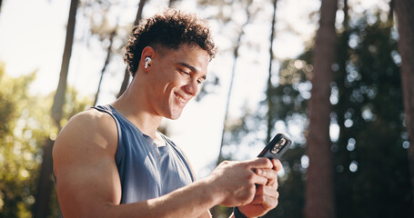 Obraz premium Exercise, happy and man in nature with phone for social media after training, fitness and workout. Sports, athlete and person typing on smartphone for health app, internet and online chat outdoor