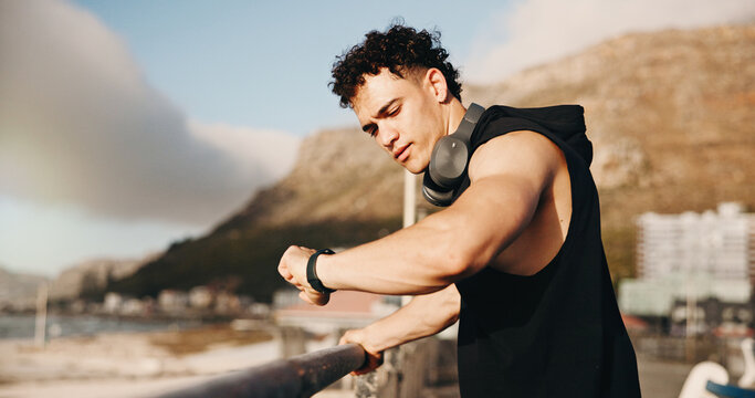 Fitness, smart watch and runner with man at beach for workout stats, distance tracking and health. Exercise performance, wellness and tech with person outdoor for speed monitor and stopwatch