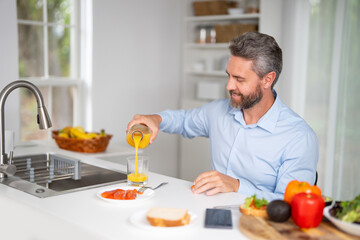 Man eats breakfast in the kitchen. Guy enjoys fresh food at the kitchen table in the morning....