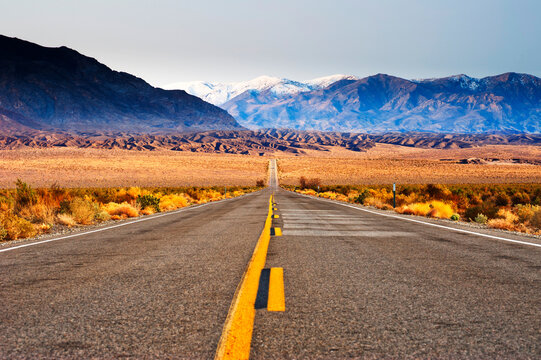 Desert Road Leading to Beautiful View of Death Valley Snow cap Mountains. Death Valley, Nevada, USA
