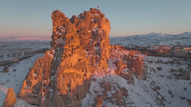 Snow-dusted Uchisar Castle In Cappadocia, Turkey, At Golden Hour Sunset. aerial drone pullback shot