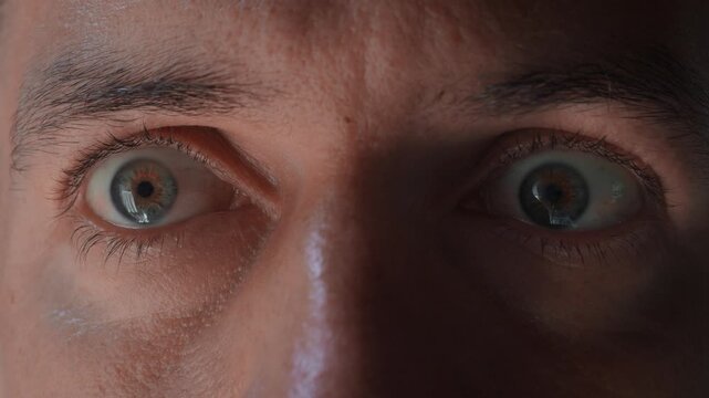 Intense human eyes close up staring at camera showing fear anxiety and awareness. Dramatic face detail with sharp focus eyes creating strong emotion concept of tension and psychological pressure.