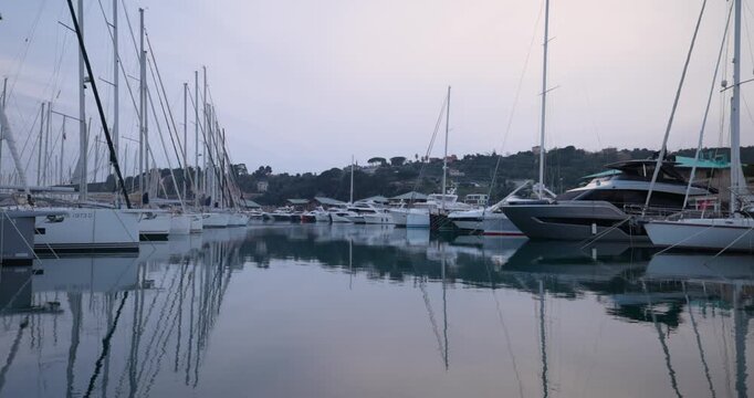 Boats moored at the harbor in Varazze, Italy, creating reflections on the calm sea