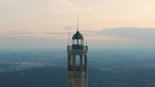 Aerial view of the historic Voltiano Lighthouse tower on Brunate hill with soft sunset light over Lake Como.
