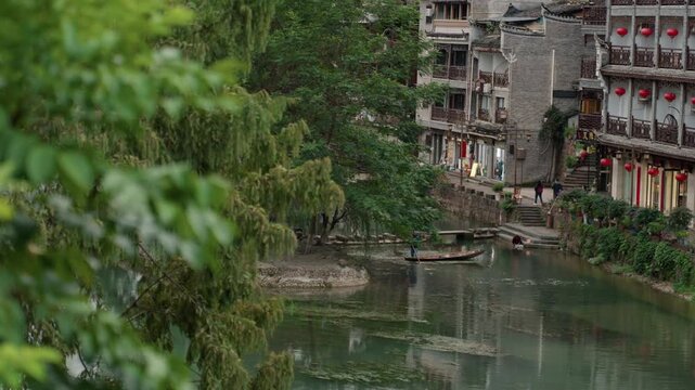 River view with willow and balconies, hidden riverside village scene with mossy stone steps, lanterns on weathered facades, laundry fluttering on lines, small wooden boat drifting, willow branches