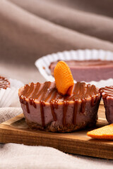 Miniature cheesecakes arranged on a wooden cutting board with a simple brown fabric background