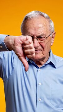 An elderly man with glasses expresses disapproval with a thumbs down gesture against a vibrant background
