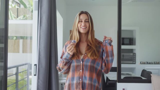 Content creator films a home vlog while holding a wireless microphone and speaking on camera. Young woman records authentic lifestyle video for social media, branding and online promotion.